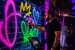 man painting on a digital graffiti wall with multiple colors