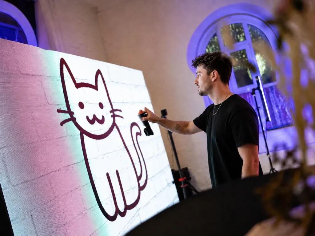 man drawing cat in a graffitty wall